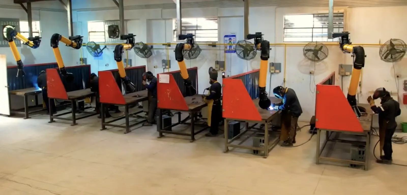 Welders working at extraction-equipped stations inside a partner facility